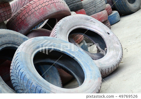 A picture of many old used tires left on a waste 49769526