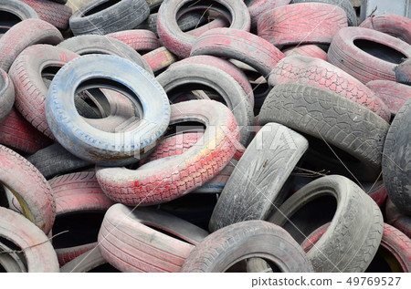 A picture of many old used tires left on a waste 49769527