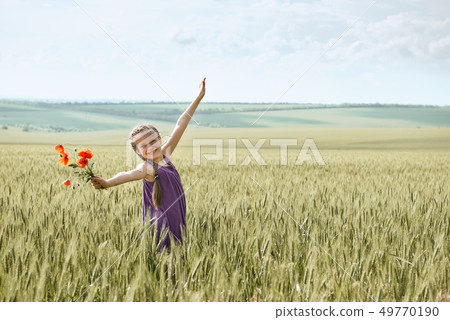girl with red tulip flowers posing in the wheat 49770190