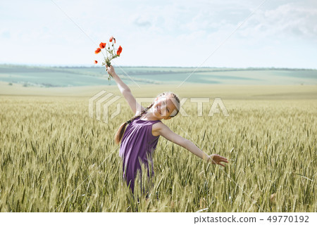 girl with red tulip flowers posing in the wheat 49770192
