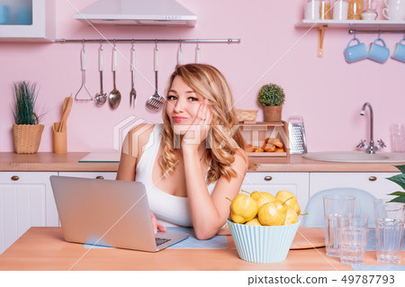 Worried and sad student female searching information in a laptop online sitting in the kitchen. Sad Worried and sad student female searching information in a laptop online sitting in the kitchen. Sad 49787793