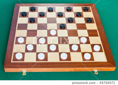 checkers on wooden board on green table 49788972