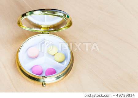 open pillbox with pink and yellow pills 49789034