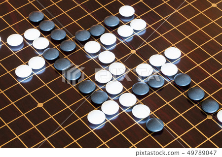 playing stones on wooden board in Go playing stones on wooden board in Go 49789047