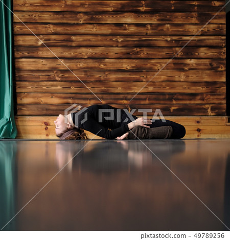 woman practicing yoga, lying in Reclining Hero exercise, Supta Virasana pose 49789256