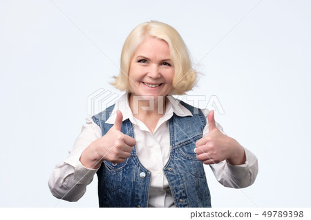 Elderly blonde european woman giving a thumb up Elderly blonde european woman giving a thumb up 49789398