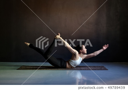 Young attractive woman practicing yoga, stretching in Salabhasana pose 49789439
