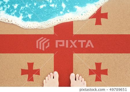 Feet on the sunny sandy beach with flag Georgia. Feet on the sunny sandy beach with flag Georgia. 49789651