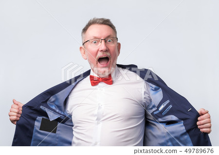 Senior man in suit and glasses looking at camera and laughing on funny joke. 49789676