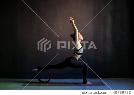 Young woman practicing yoga, standing in Warrior one exercise, Virabhadrasana 49789758