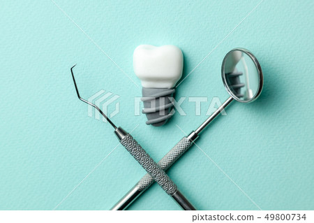 White teeth implants on green mint background and dentist tools mirror, hook. 49800734