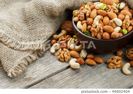 Wooden bowl with nuts on a wooden background, near 49802404