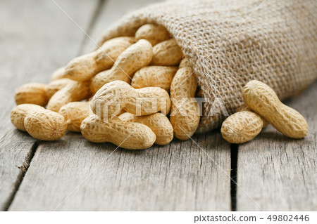 Peanuts in a miniature burlap bag on old, gray 49802446