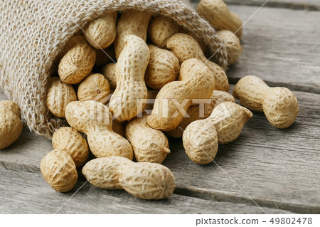 Peanuts in a miniature burlap bag on old, gray Peanuts in a miniature burlap bag on old, gray 49802478