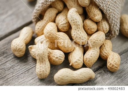Peanuts in a miniature burlap bag on old, gray Peanuts in a miniature burlap bag on old, gray 49802483
