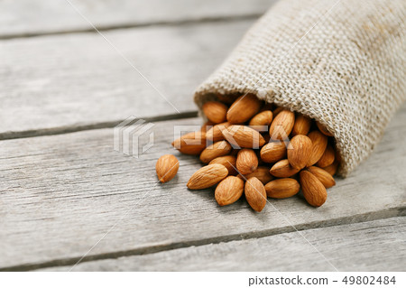 Almond nuts in a burlap bag on a wooden gray Almond nuts in a burlap bag on a wooden gray 49802484