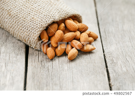 Almond nuts in a burlap bag on a wooden gray Almond nuts in a burlap bag on a wooden gray 49802567
