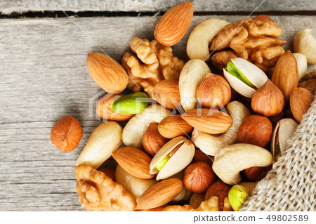 Mix of different nuts in a wooden cup against the 49802589
