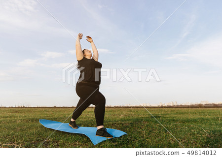 Young woman doing yoga exercises in the meadow Young woman doing yoga exercises in the meadow 49814012