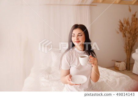 Young smiling woman enjoy morning coffee in bed Young smiling woman enjoy morning coffee in bed 49814143