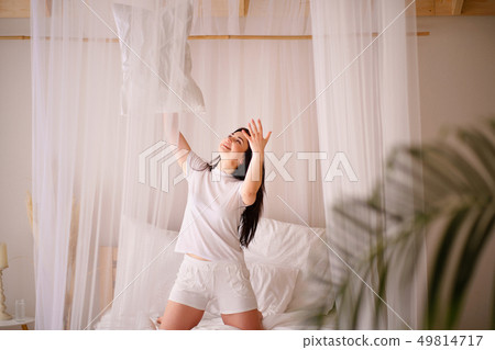 Beautiful young girl jumping in bed after wake up 49814717