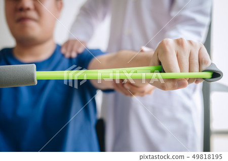 Doctor physiotherapist assisting a male patient 49818195