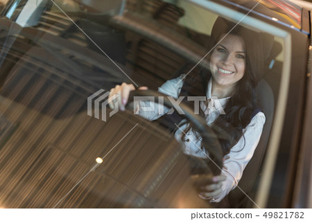 Happy woman buyer examines her new vehicle in car dealership Happy woman buyer examines her new vehicle in car dealership 49821782