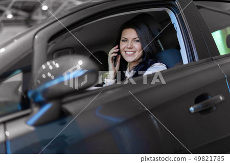 Happy woman buyer sitting in her new vehicle in car dealership Happy woman buyer sitting in her new vehicle in car dealership 49821785