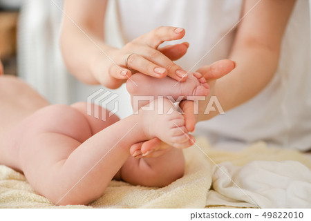 Young woman massage gently baby toes, close up Young woman massage gently baby toes, close up 49822010