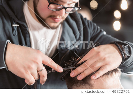 Close-up Hair cutting with metal scissors. Master cuts hair and beard of men in the barbershop Close-up Hair cutting with metal scissors. Master cuts hair and beard of men in the barbershop 49822701