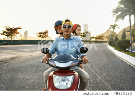 Parents with their little kid riding motorcycle on sunny city street Parents with their little kid riding motorcycle on sunny city street 49825180