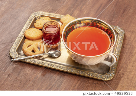 Danish butter cookies on a vintage tray with a cup of tea and jam on a dark rustic wooden background Danish butter cookies on a vintage tray with a cup of tea and jam on a dark rustic wooden background 49829553