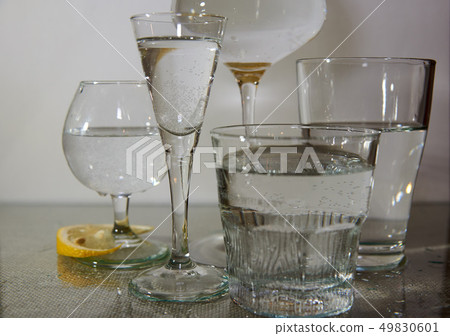 Different glasses are on the table, filled with clean water.Next slice of lemon. Different glasses are on the table, filled with clean water.Next slice of lemon. 49830601