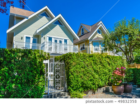 Residential house with entrance gate and green hedge in front. 49832358