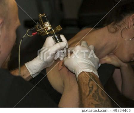 a man tattooing a woman 49834405