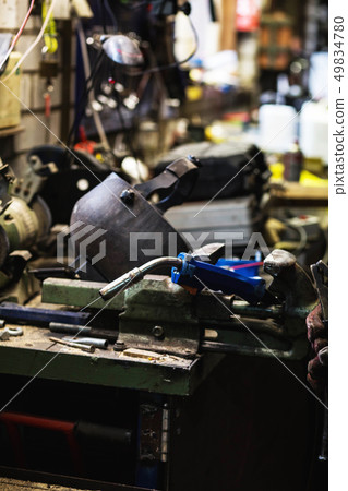 welder is welding metal part in garage. with protective mask, industrial steel welder 49834780