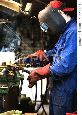 welder is welding metal part in garage. with protective mask, industrial steel welder 49834781