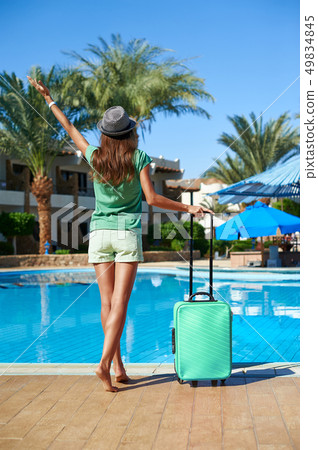 Travel, summer holidays and vacation concept - Beautiful woman walking near hotel pool area with 49834845