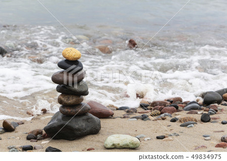 A pyramid of stones with a bright stone at the top 49834975