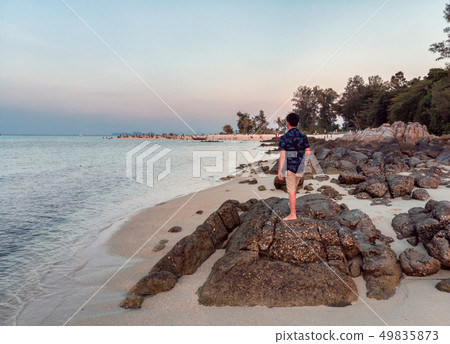 Man standing on coastline with tourists in 49835873