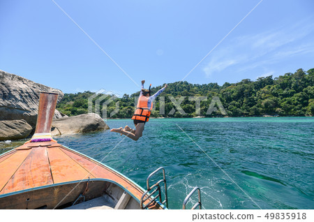 Woman tourist jumping on wooden boat in tropical Woman tourist jumping on wooden boat in tropical 49835918