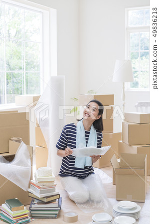 Smiling woman sitting and wrapping dishes Smiling woman sitting and wrapping dishes 49836218
