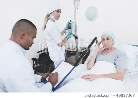 The nurse sets the woman a dropper. 49837367