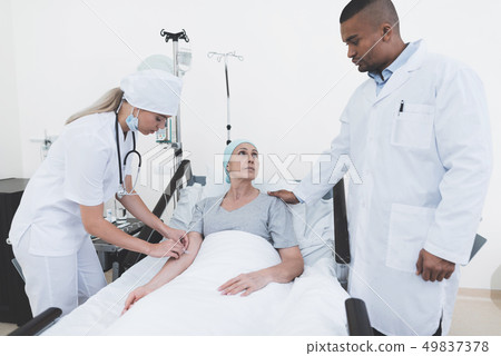 A nurse puts a woman with a cancer with a dropper. A nurse puts a woman with a cancer with a dropper. 49837378