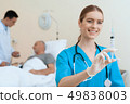 man lies on a cot. Doctor and a nurse help him. 49838003