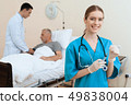 man lies on a cot. Doctor and a nurse help him. 49838004