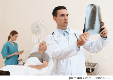 man lies on a cot. Doctor and a nurse help him. man lies on a cot. Doctor and a nurse help him. 49838009
