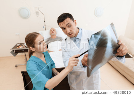 man lies on a cot. Doctor and a nurse help him. man lies on a cot. Doctor and a nurse help him. 49838010