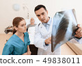 man lies on a cot. Doctor and a nurse help him. 49838011