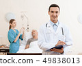 man lies on a cot. Doctor and a nurse help him. 49838013